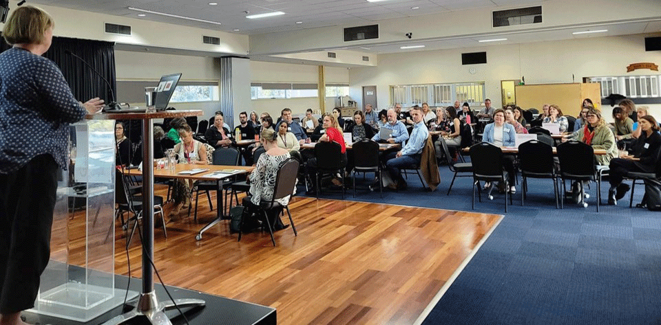 Photo of people meeting in a large room for Turn Input into Action forum